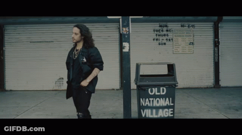 Man Standing Next To Old National Village Garbage Can GIF