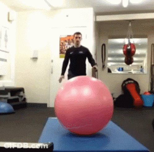 Man Standing Next To Pink Ball On Blue Mat GIF