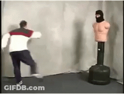 Man Standing Next To Punching Bag And Mannequin Wearing Mask GIF