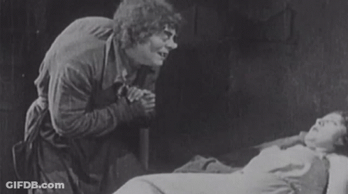 Man Standing Next To Woman Laying In Bed GIF