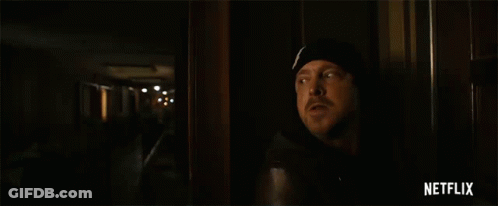 Man Standing Next To Yellow Netflix Tape In Dark Room GIF