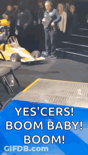 Man Standing Next To Yellow Race Car Saying Yes Cers Boom Baby Boom GIF