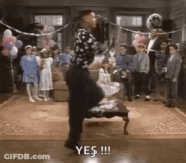Man Standing On One Leg In Front Of Microphone In Living Room With Balloons GIF
