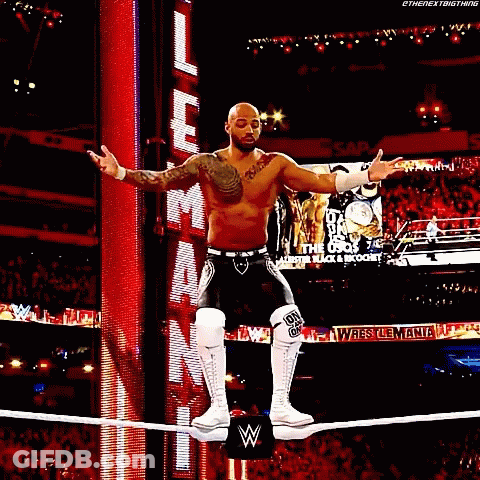 Man Standing On Rope In Wrestling Ring With Arms Up GIF
