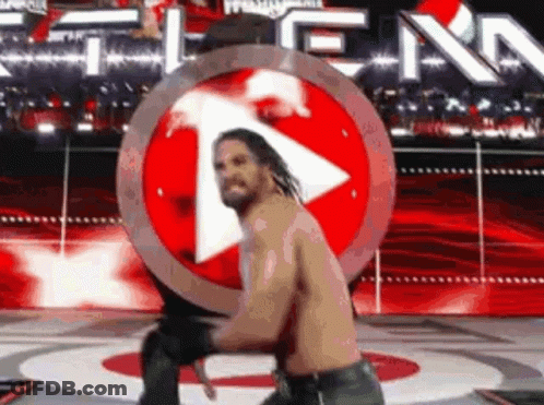 Man Standing On Stage In Front Of Red Play Button GIF