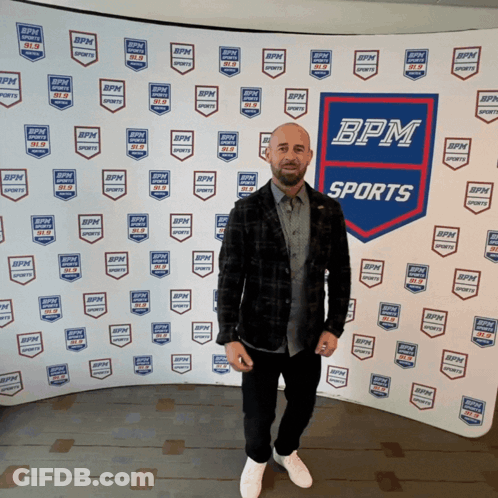 Man Stands Before Wall With BPM Sports Logos GIF