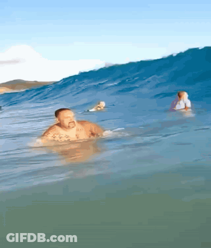 Man Swimming While Surfer Rides Wave GIF
