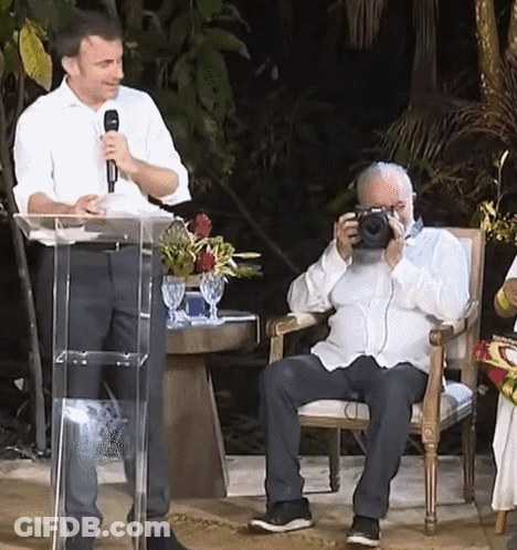 Man Taking Picture At Podium With Microphone GIF