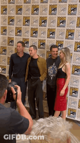 Man Taking Picture Of Group In Front Of Comic Con Wall GIF