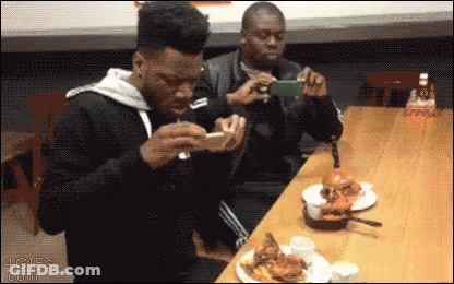 Man Taking Picture Of Man Eating Hamburger GIF