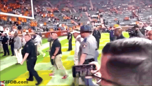 Man Taking Picture Of Police Officer On Football Field GIF