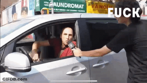 Man Talking Into Microphone In Front Of Laundromat Sign GIF