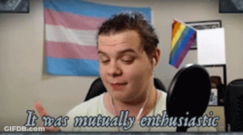 Man Talking Into Microphone With Rainbow And Transgender Flags GIF