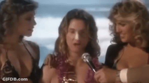 Man Talking Into Microphone With Two Women In Bikinis GIF