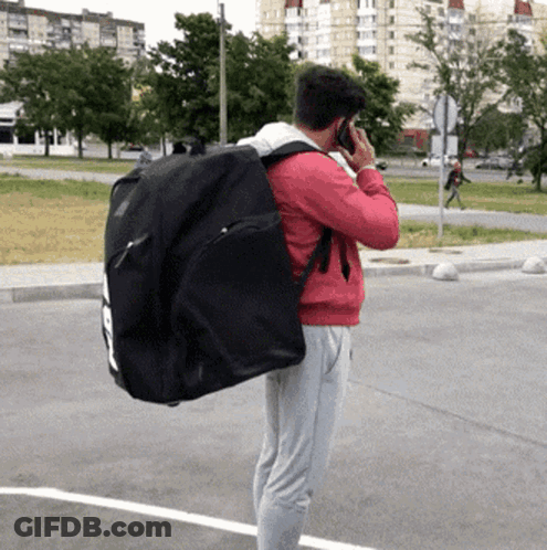 Man Talking On Cell Phone Carrying Black Bag GIF