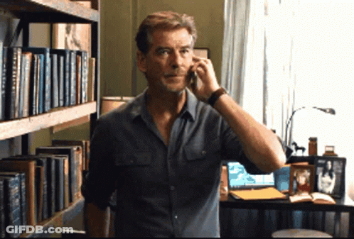 Man Talking On Cell Phone In Front Of Bookshelf With A Brief History GIF