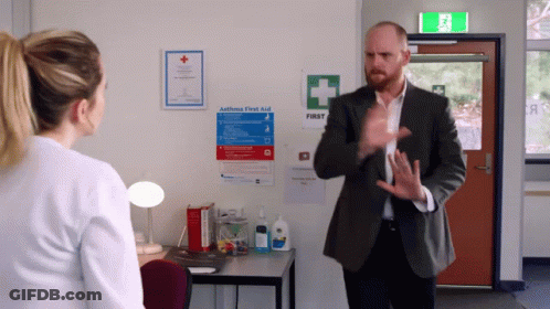 Man Talking To Woman In Front Of First Aid Sign GIF