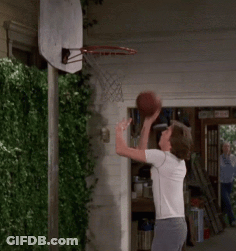 Man Throwing Basketball Through Hoop In Front Of Garage Door GIF