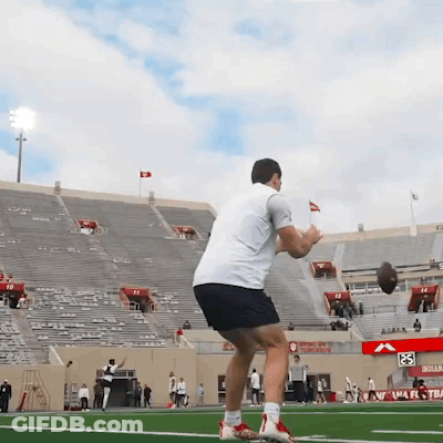 Man Throwing Football In Front Of Stadium With Tomorrow Sign GIF