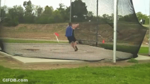 Man Throwing Frisbee In Field Behind Net GIF