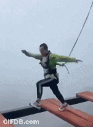 Man Walking Across Bridge With Arms Outstretched GIF