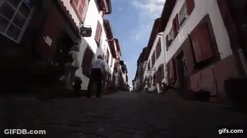 Man Walking Cobblestone Street With Gifs.com Sign GIF