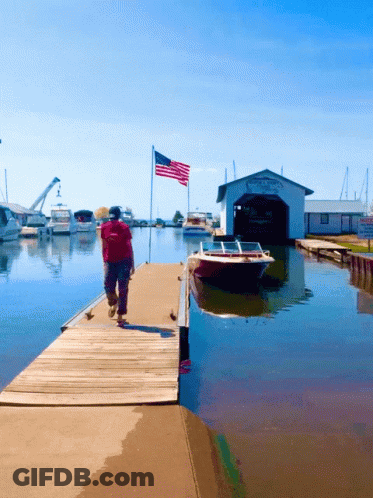 Man Walking Down Dock Past Boat Shed Saying Yacht & Yacht GIF