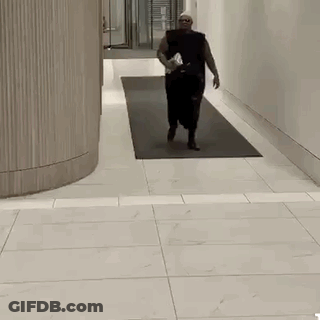 Man Walking Down Hallway With Water Bottle GIF