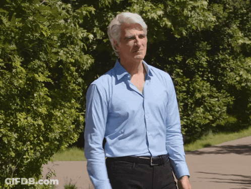 Man Walking Down Path Blue Shirt Black Pants GIF