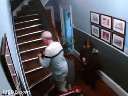 Man Walking Down Stairs While Woman Sits On Chair GIF