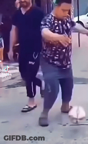 Man Walking Down Street Holding Beer GIF