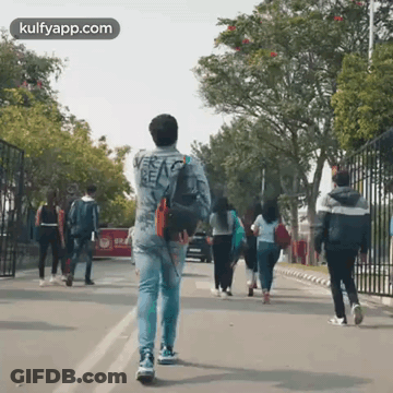 Man Walking Down Street With Group Behind Him GIF