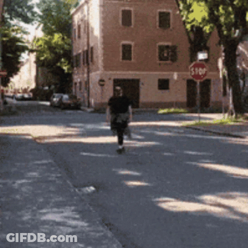 Man Walking Down Street With Stop Sign GIF