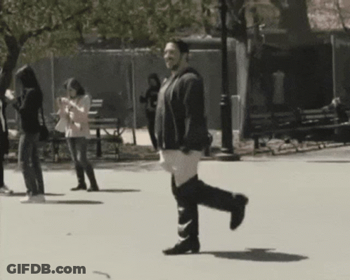 Man Walking In Park Looking At Phone GIF