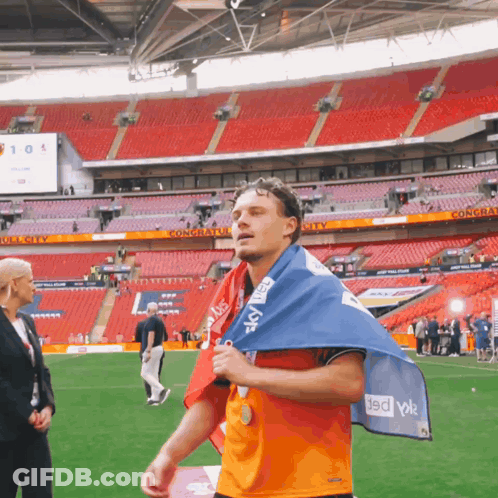 Man Walking On Field Holding Flag Saying Sky GIF