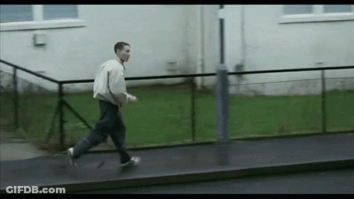 Man Walking On Sidewalk Next To Building GIF