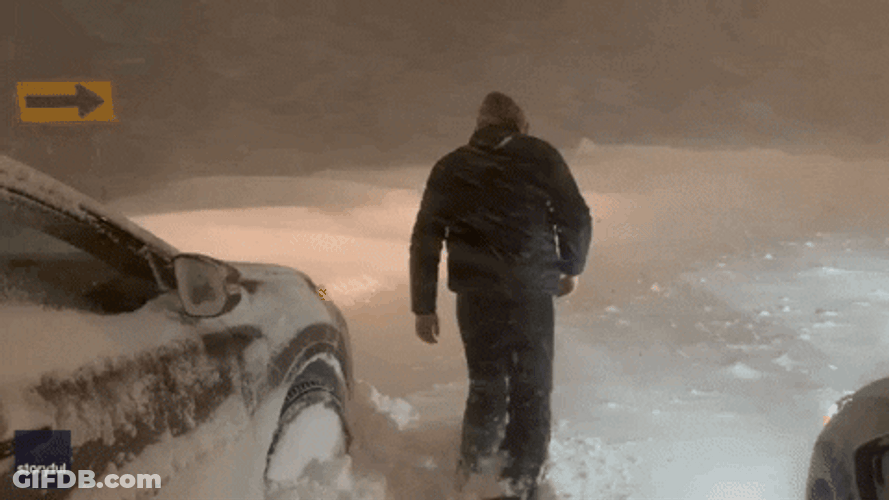 Man Walking On Snowy Road Amid Bomb Cyclone GIF