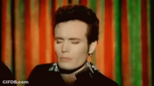 Man Wearing Choker Eyes Closed Before Colorful Curtain GIF