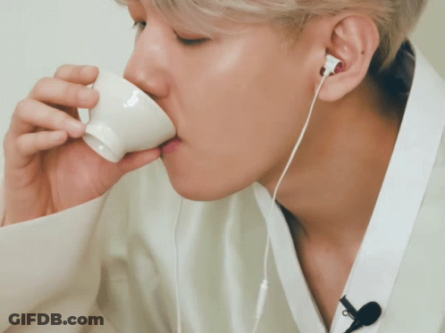 Man Wearing Earbuds Drinking From Small White Cup GIF