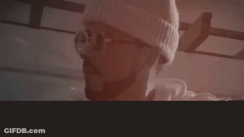 Man Wearing Glasses And Beanie Sitting On Ledge GIF