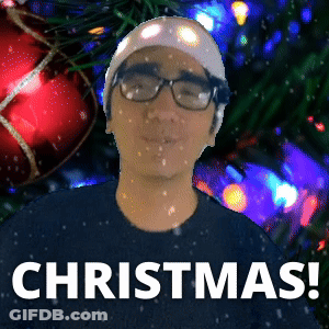 Man Wearing Glasses And Beanie Standing In Front Of Christmas Tree GIF