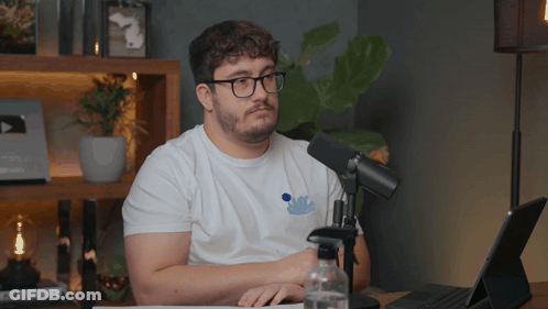Man Wearing Glasses Sitting In Front Of Microphone GIF