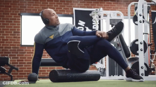 Man Wearing Headphones Stretching Legs On Foam Roller GIF