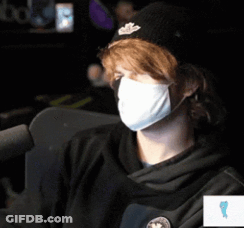 Man Wearing Mask And Hat Sitting At Microphone GIF
