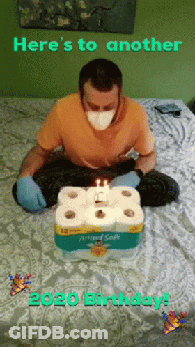 Man Wearing Mask Sitting On Bed With Toilet Paper Cake GIF