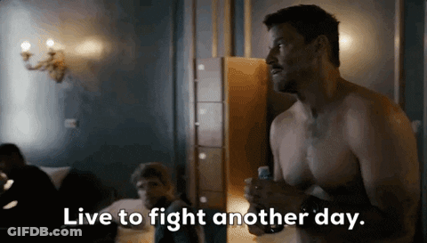 Man Wearing Mask Talking To Another Man In Dark Room GIF