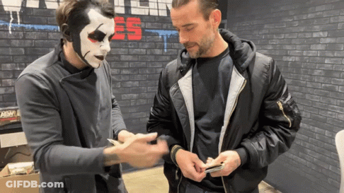 Man Wearing Mask Talking To Man With Cell Phone GIF