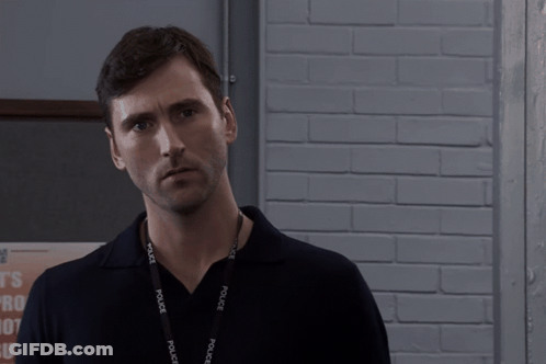 Man Wearing Police Lanyard Looks At Camera GIF