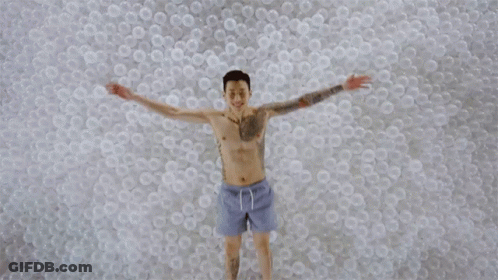 Man With Arm Tattoo Lying In Plastic Balls GIF
