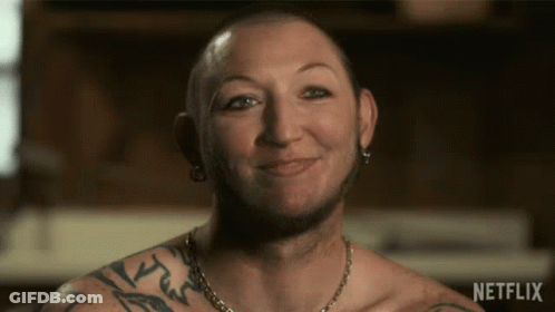 Man With Arm Tattoo Smiling In Front Of Netflix Sign GIF